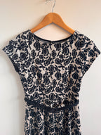Black floral patterned dress on a wooden hanger against a white background