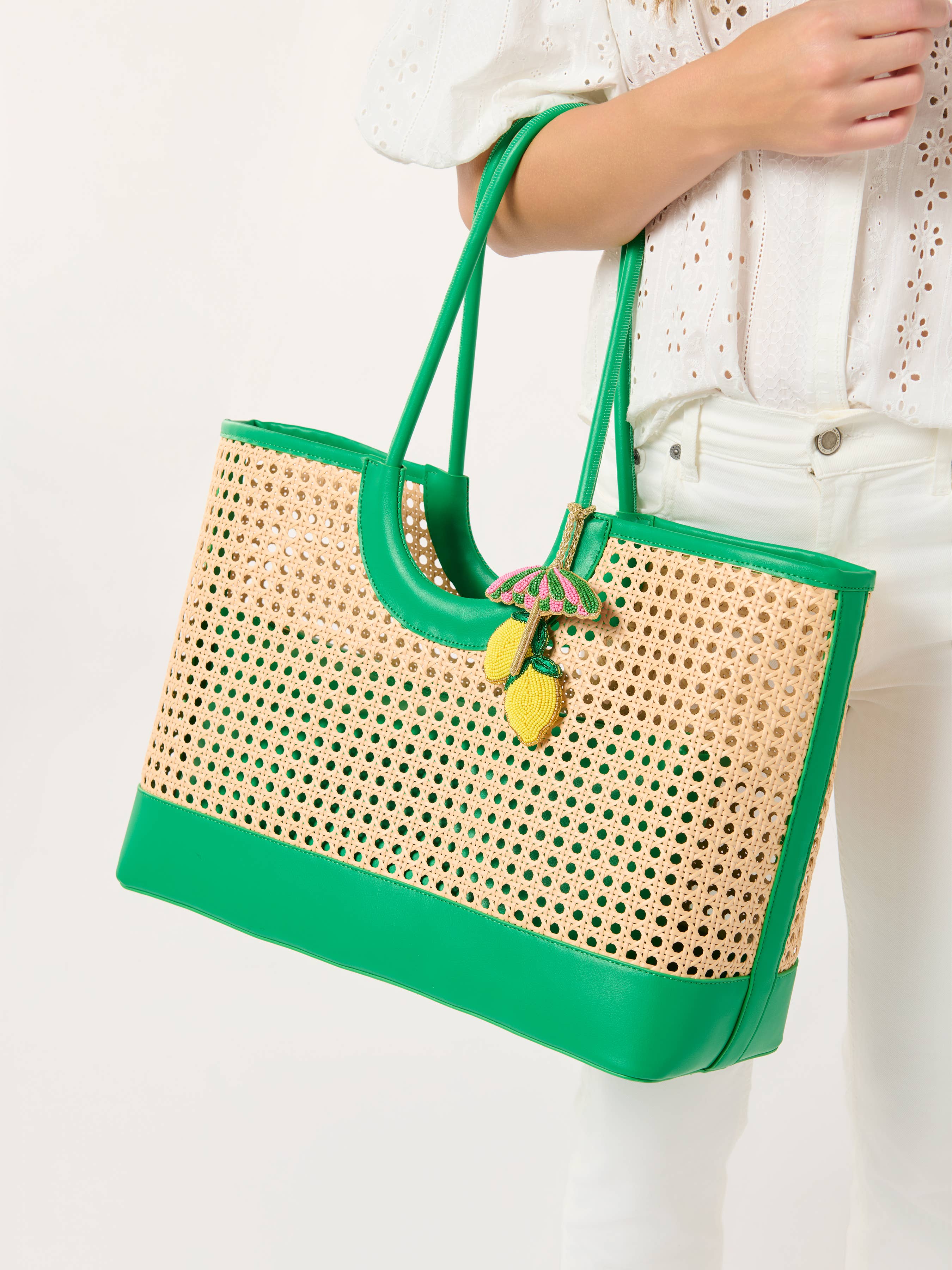 Green and beige woven handbag held by a person on a white background