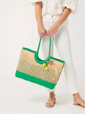 Person holding a green and beige woven handbag on a white background