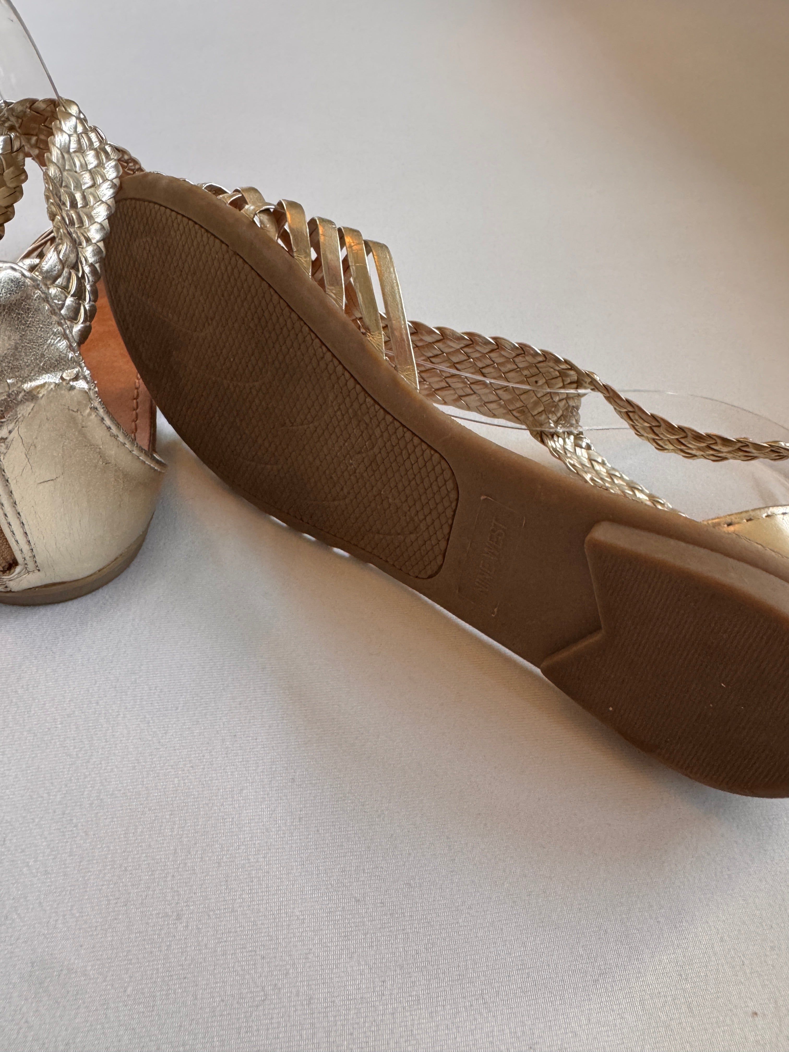 Soles of gold woven sandals on a white background
