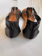 Back of black sandals showing a zip back closure on a white background