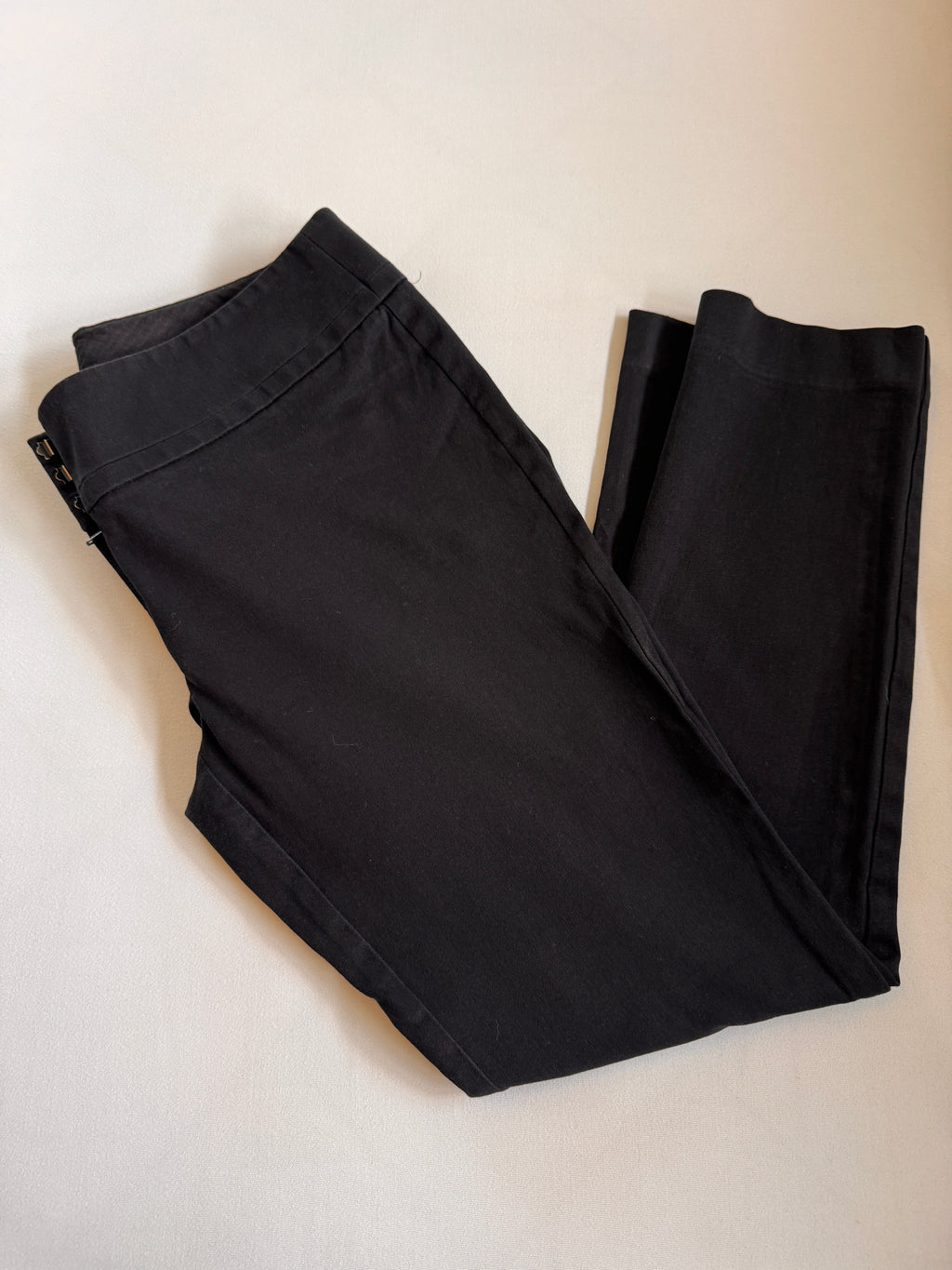 Folded black pants on a light beige background