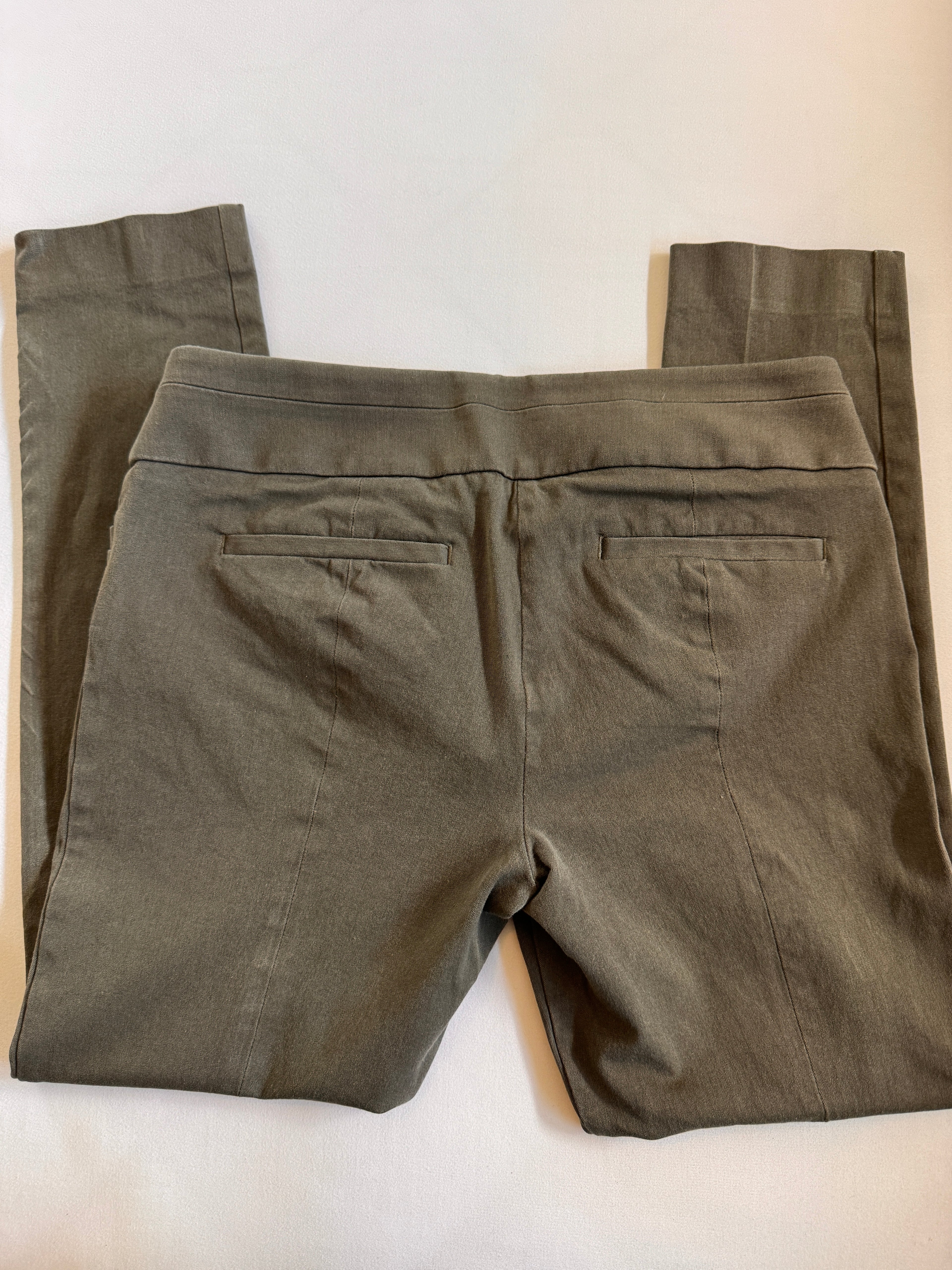 Folded green pants on a white surface