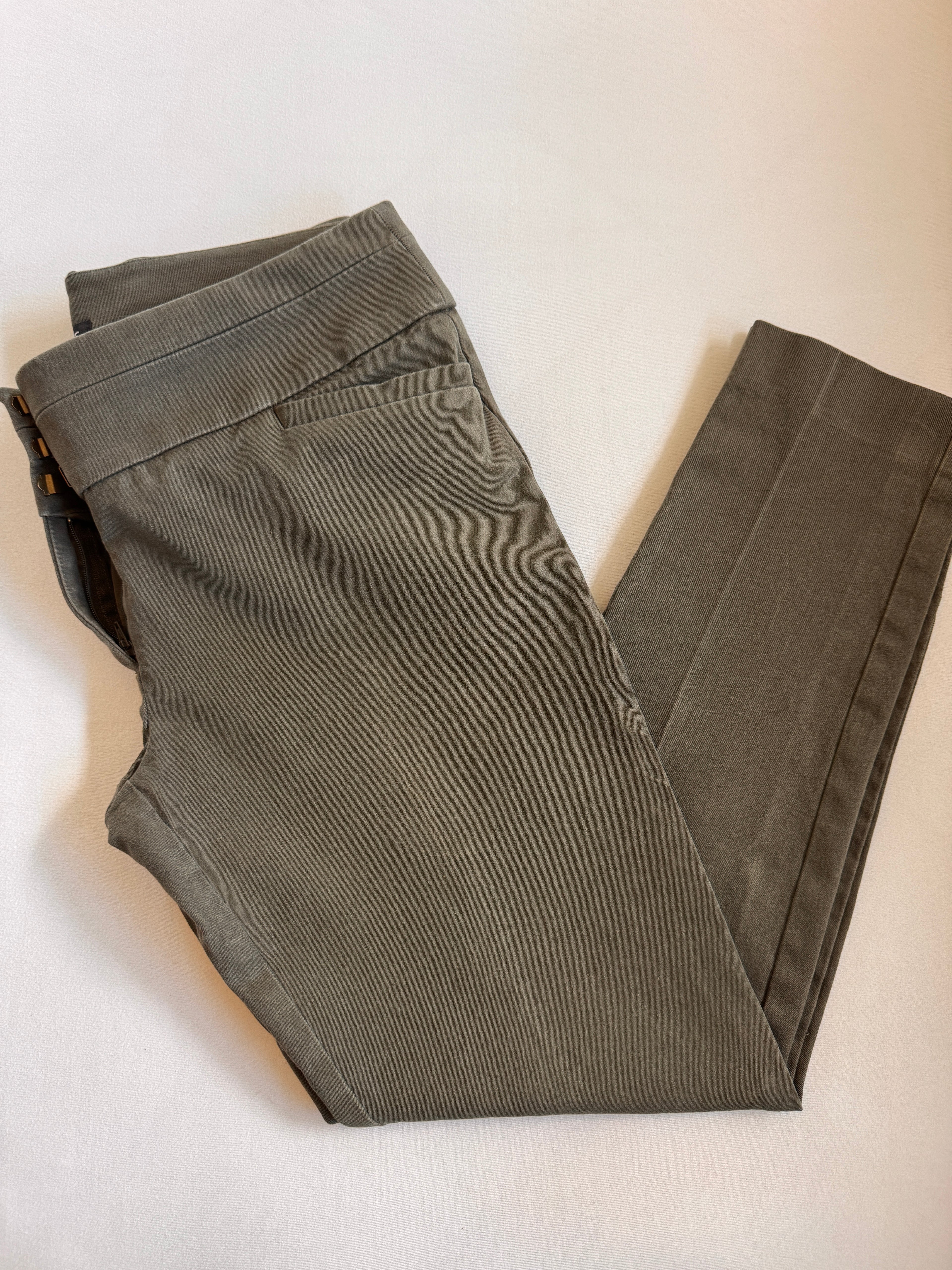 Olive toned pants folded on a light background