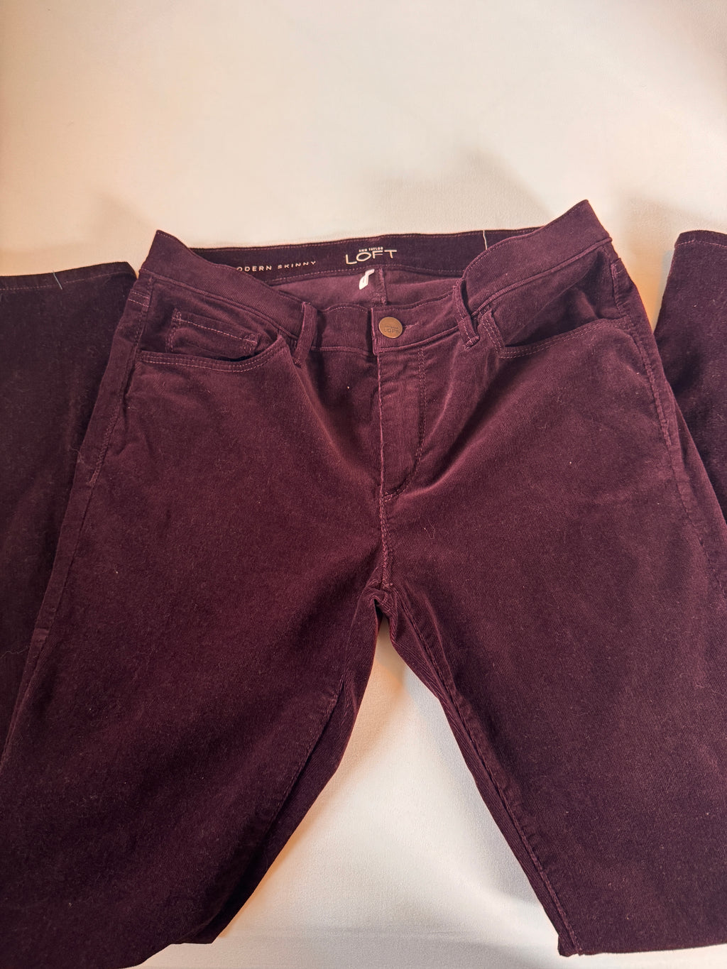 Folded maroon pants on a light beige surface