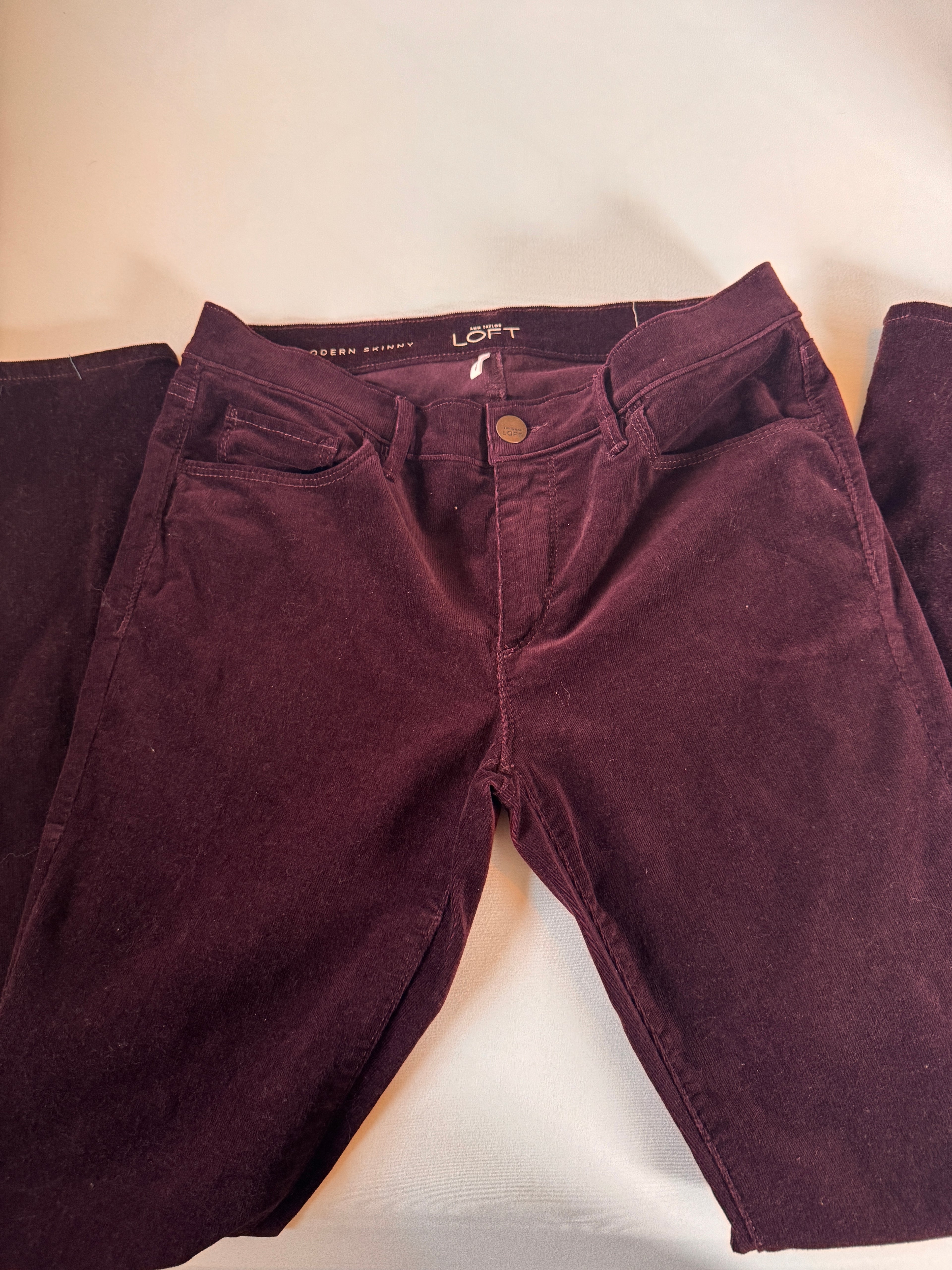 Folded maroon pants on a light beige surface
