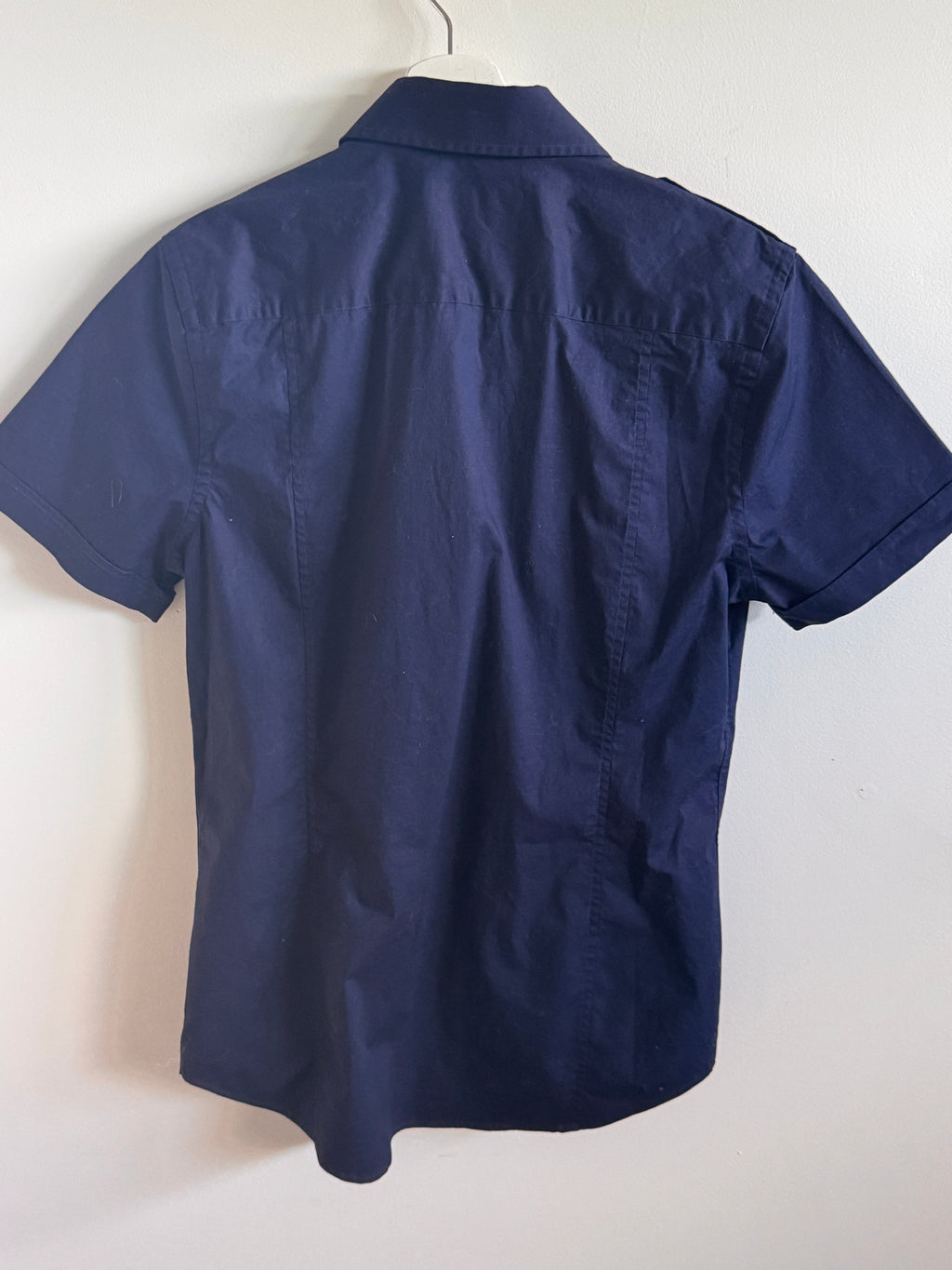 Navy blue short-sleeve shirt on a hanger against a white background