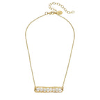Gold necklace with a bar pendant featuring pearls on a white background
