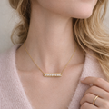 Gold necklace with pearls worn by a person, close-up on neck and chest area.