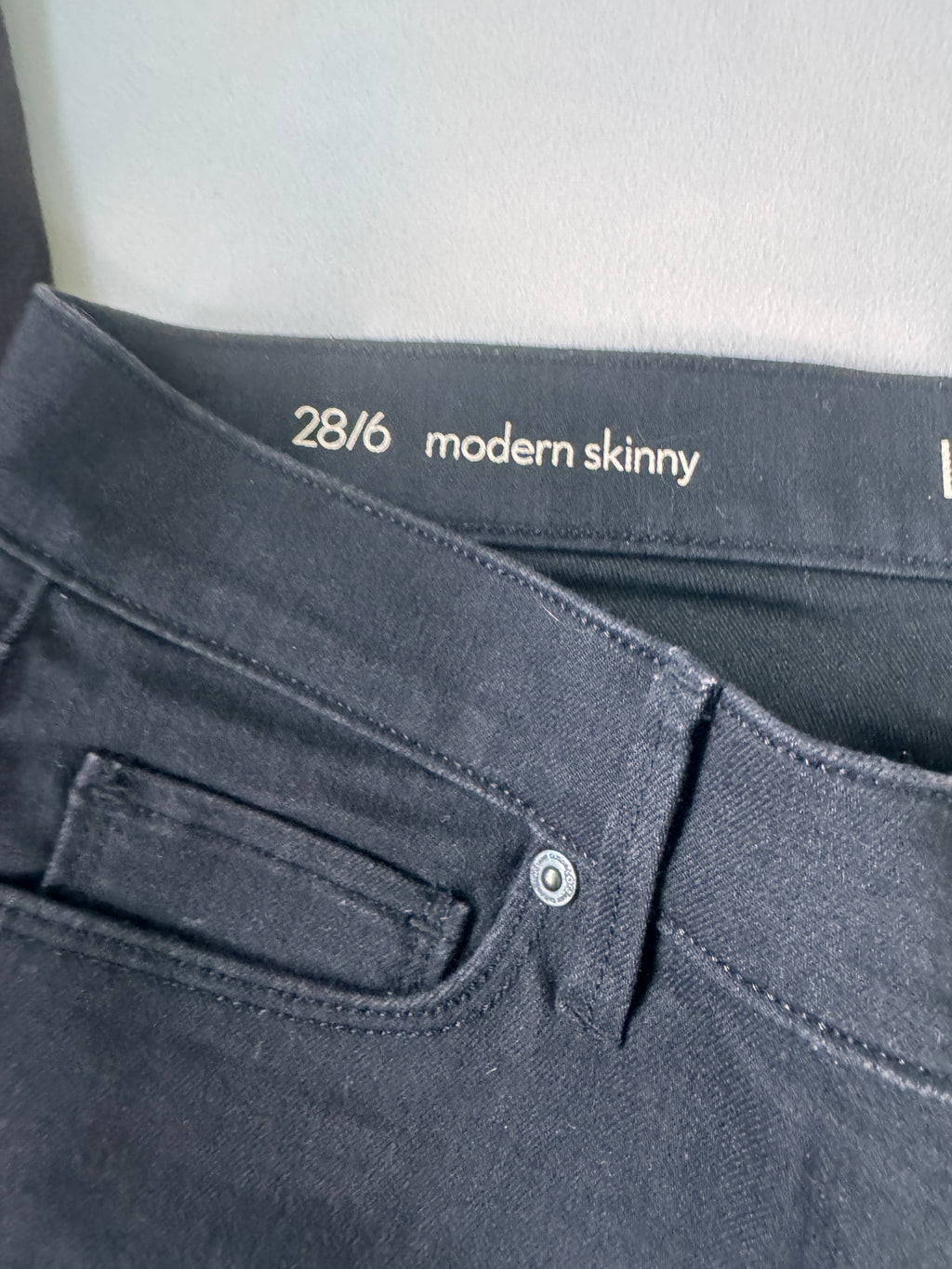 Close-up of black  jeans with 'modern skinny' text and size label on a white background