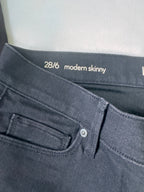 Close-up of black  jeans with 'modern skinny' text and size label on a white background