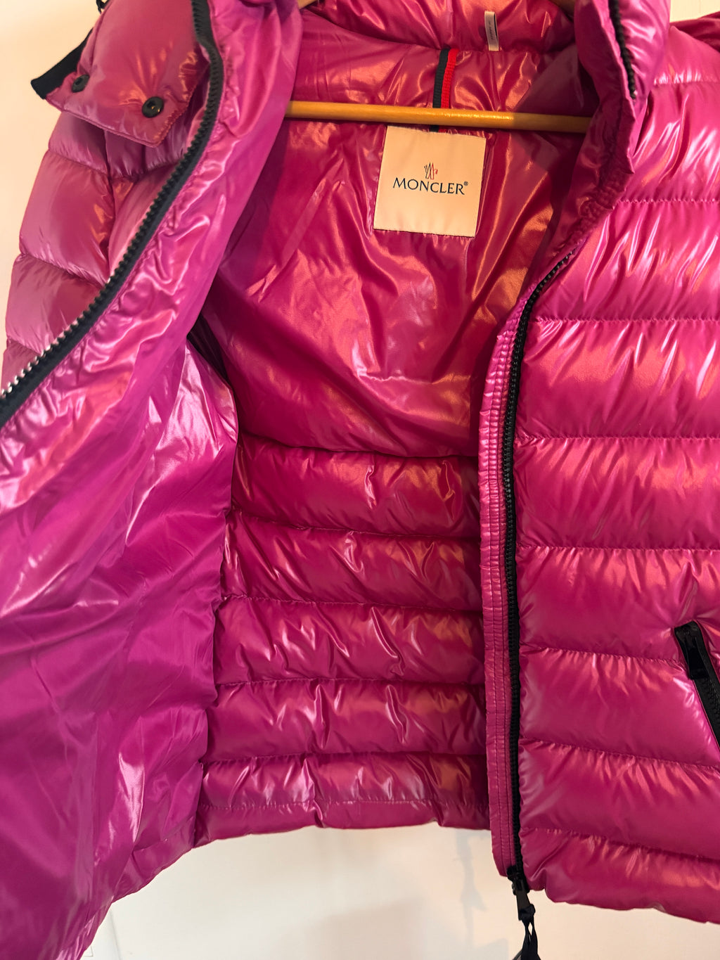 Close-up of a pink puffer jacket with a visible brand label on a white background