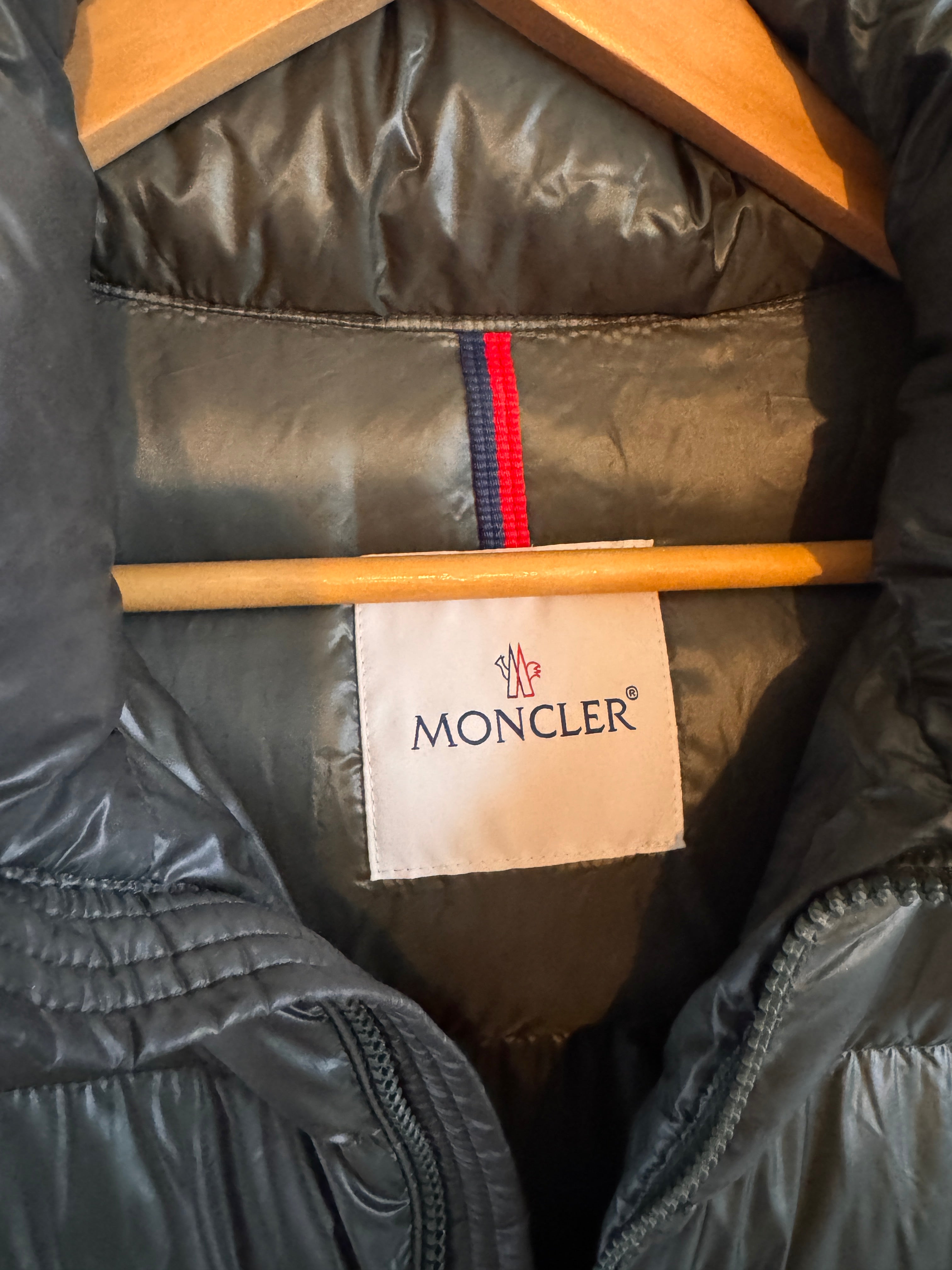Close-up of a Moncler jacket with a brand label and wooden stick inside.