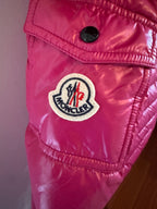 Close-up of a pink jacket with a brand logo on a neutral background