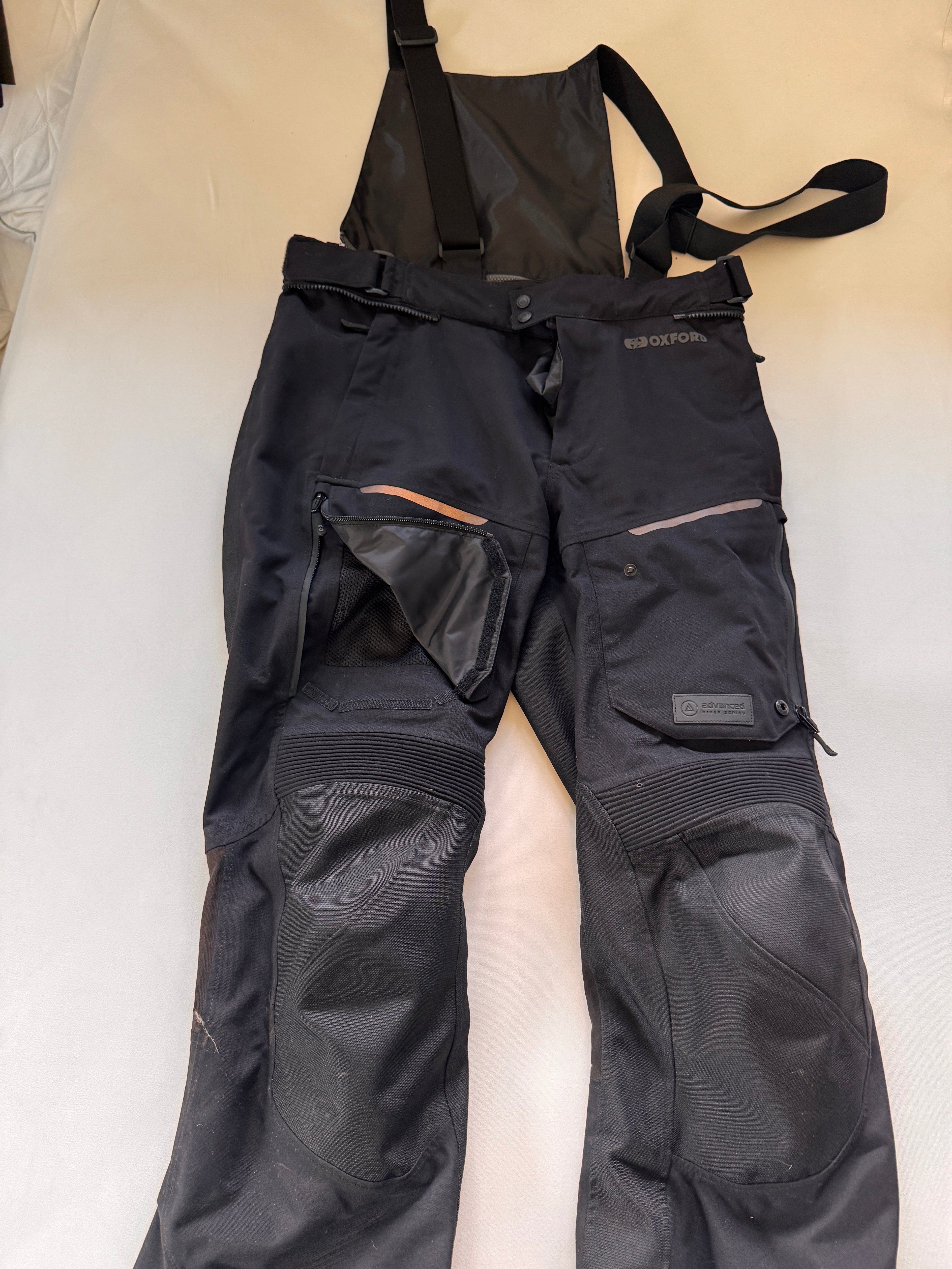 motorcycle riding pants with suspenders shown on a white background with unzipped front pocket