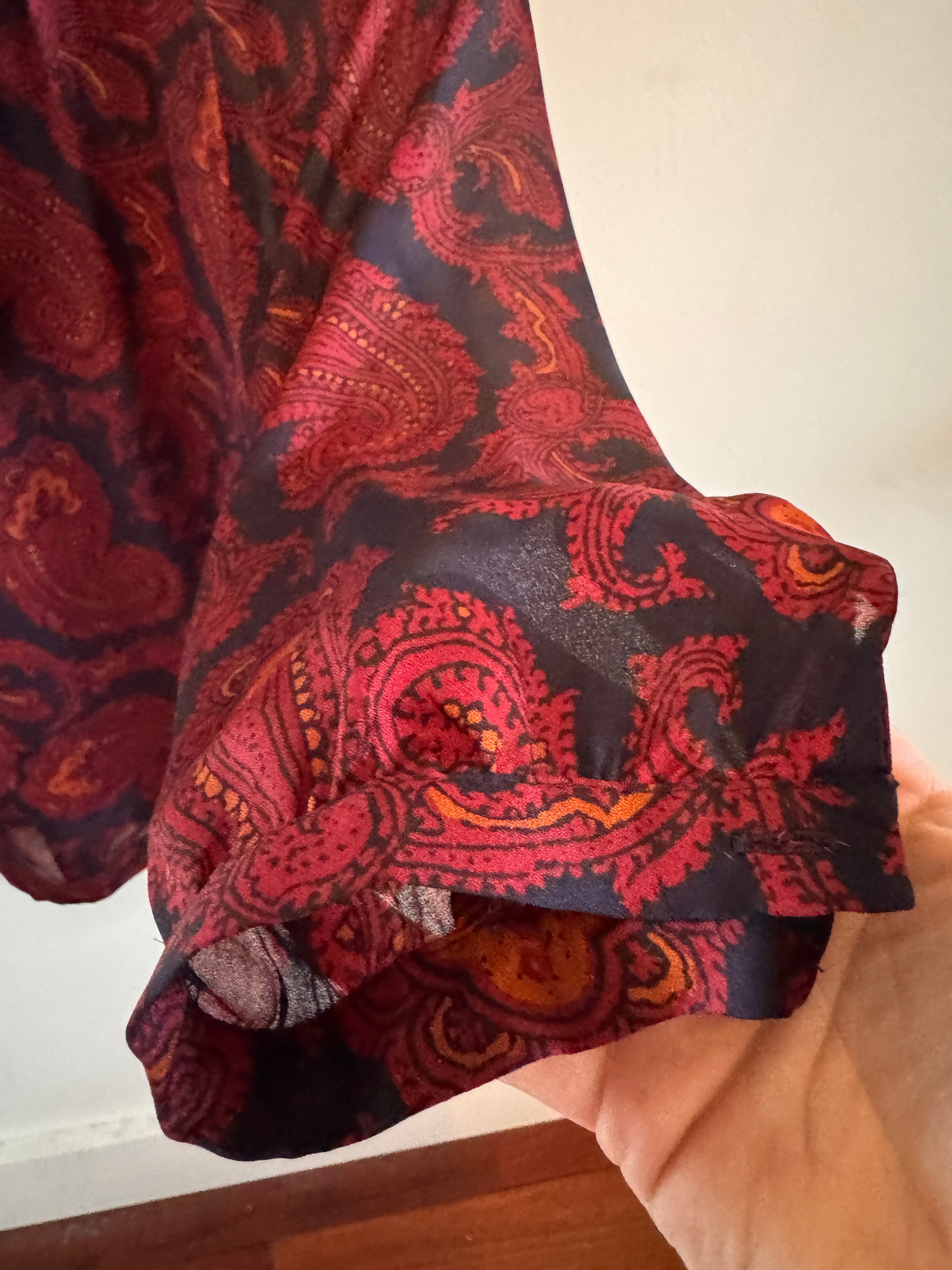 Red and black patterned fabric held by a hand against a neutral background