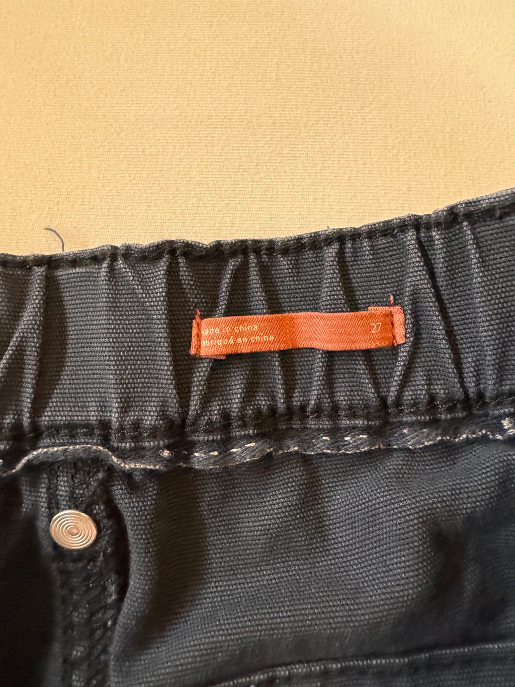 Close-up of black denim fabric with a brand label on a beige background