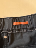 Close-up of black denim fabric with a brand label on a beige background