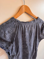 Blue floral top on a wooden hanger against a beige background