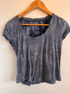 Blue textured shirt on a wooden hanger against a beige background