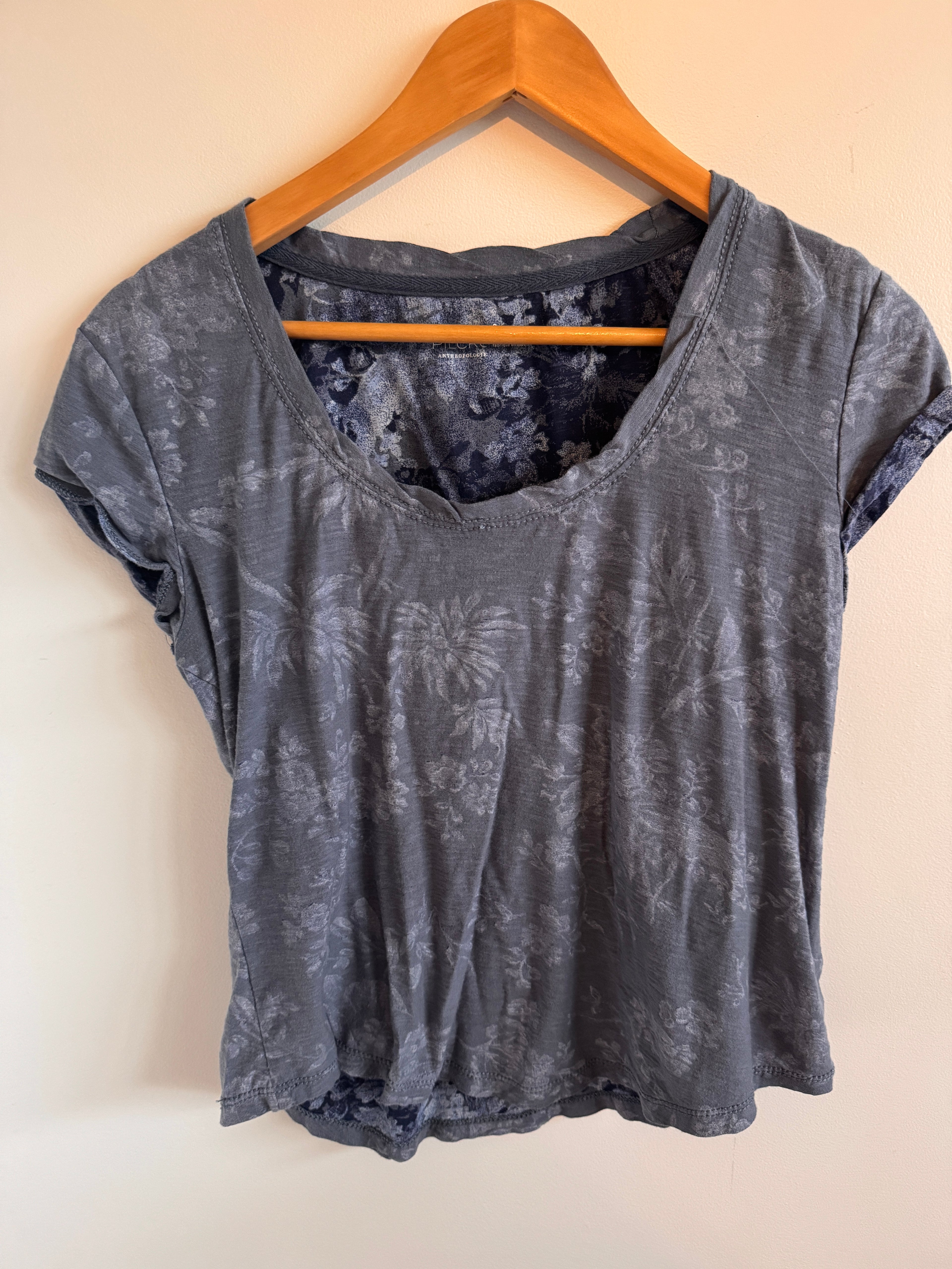 Blue textured shirt on a wooden hanger against a beige background