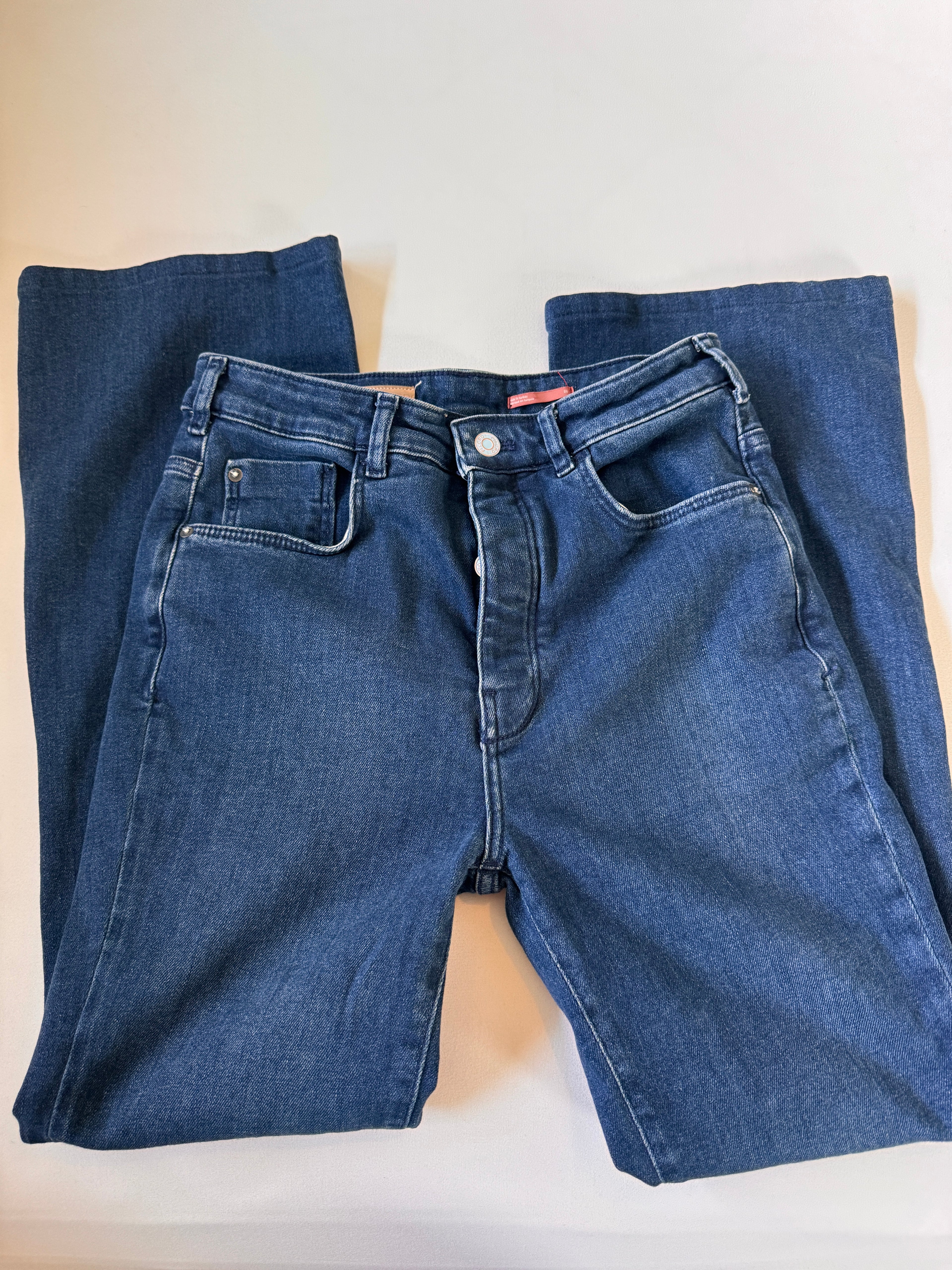Folded pair of blue jeans on a light beige surface