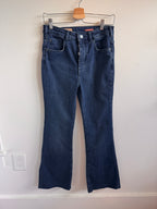 Pair of blue jeans on a hanger against a white wall