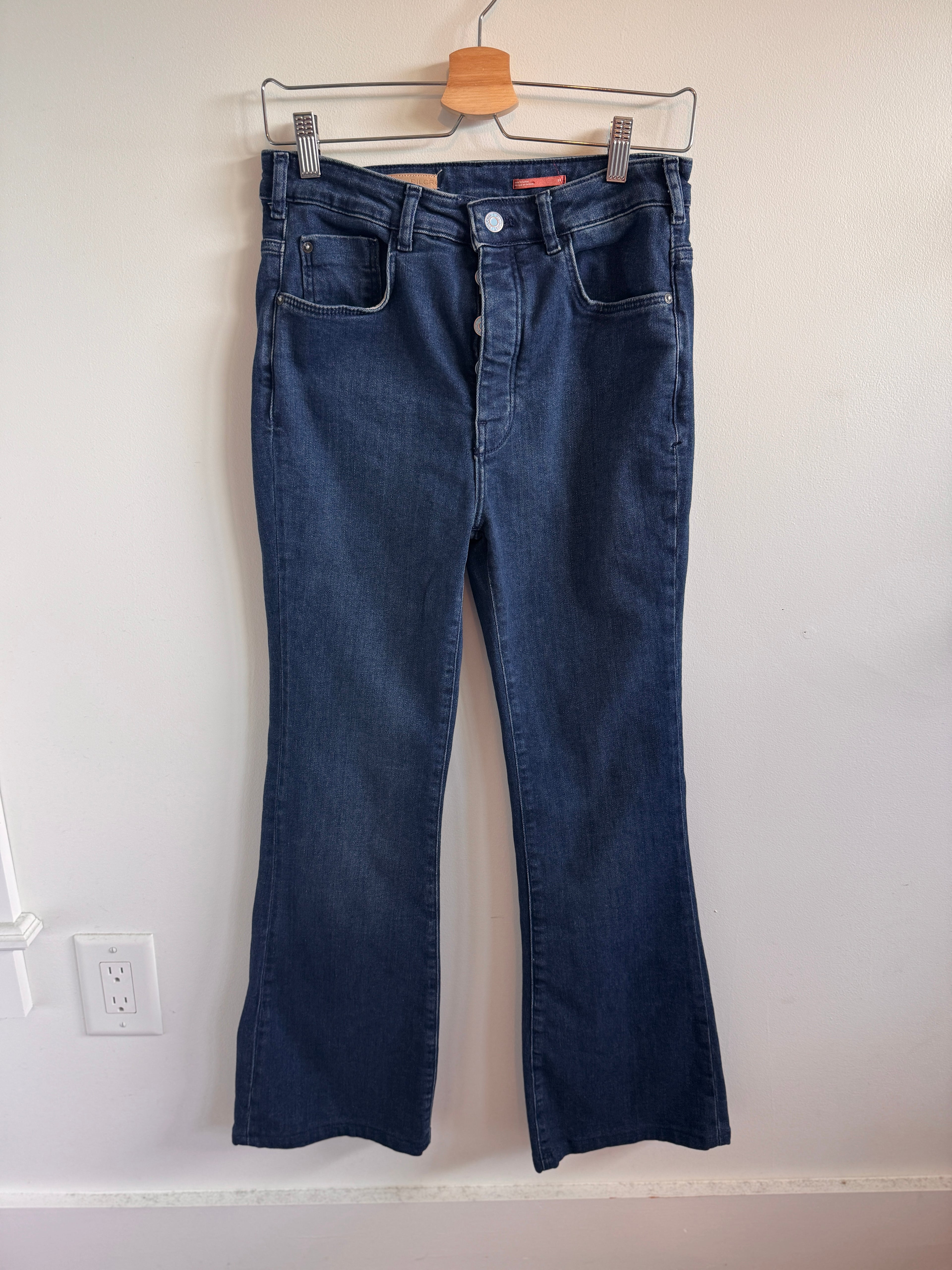 Pair of blue jeans on a hanger against a white wall