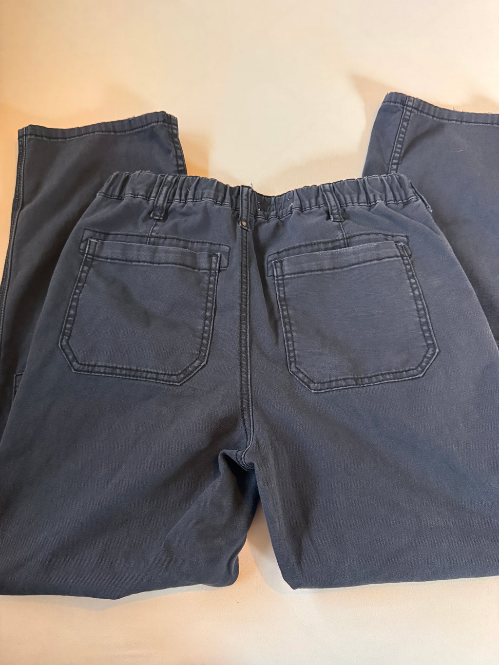 Folded dark blue pants on a beige surface