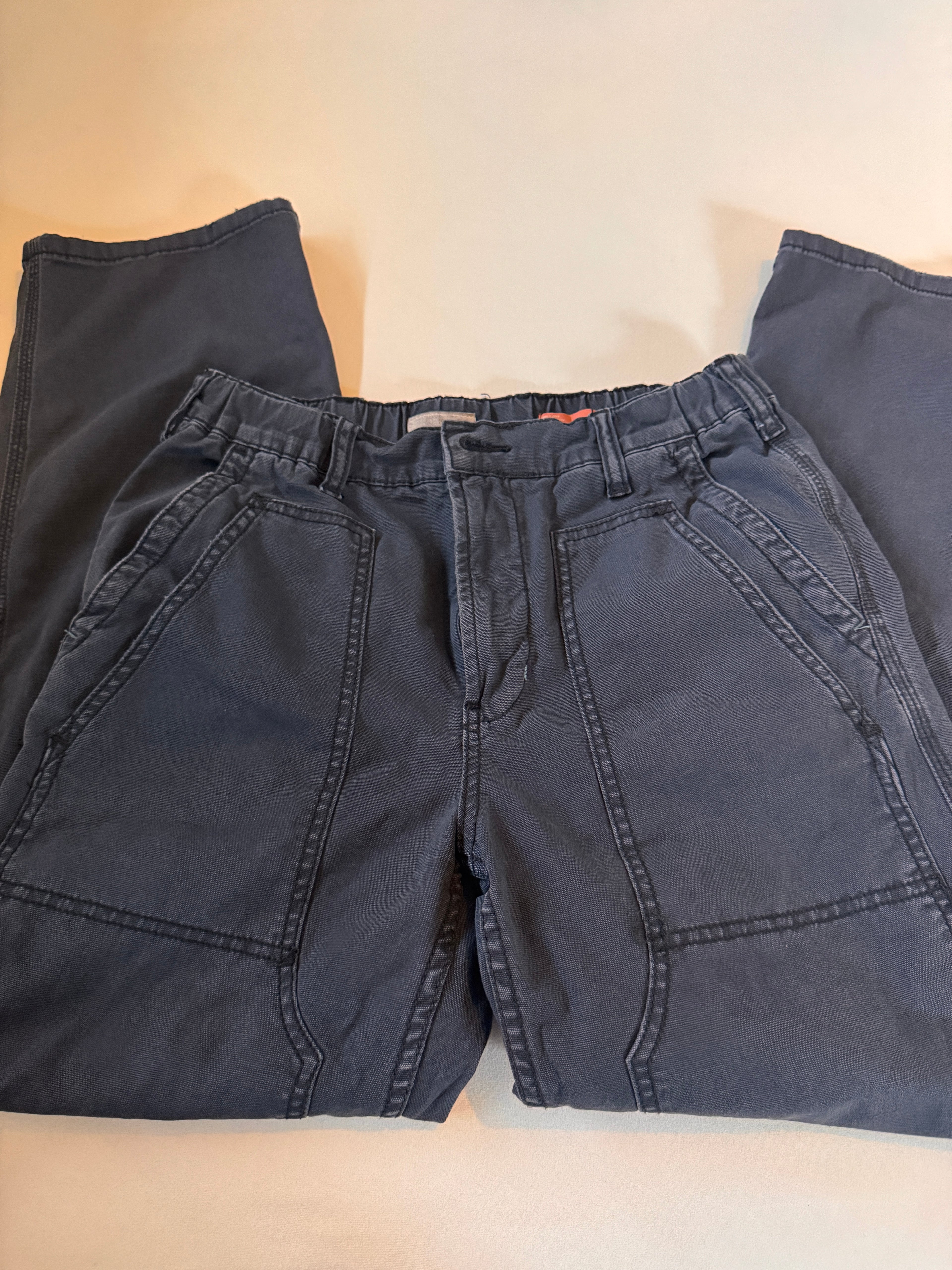 Folded dark blue pants on a beige surface