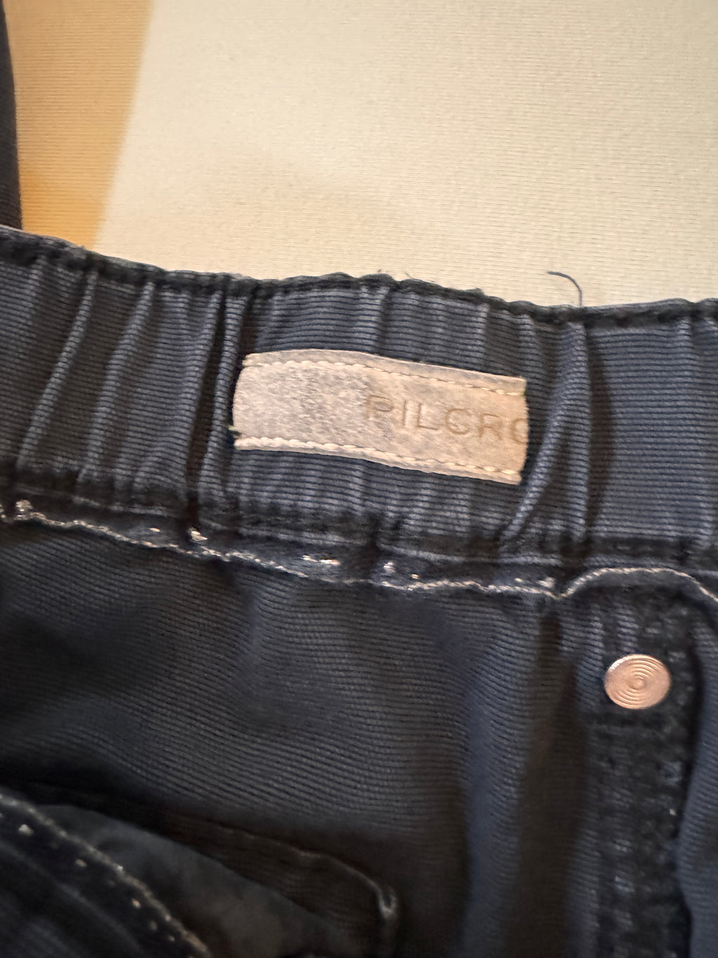 Close-up of dark blue denim fabric with a brand label on a beige background
