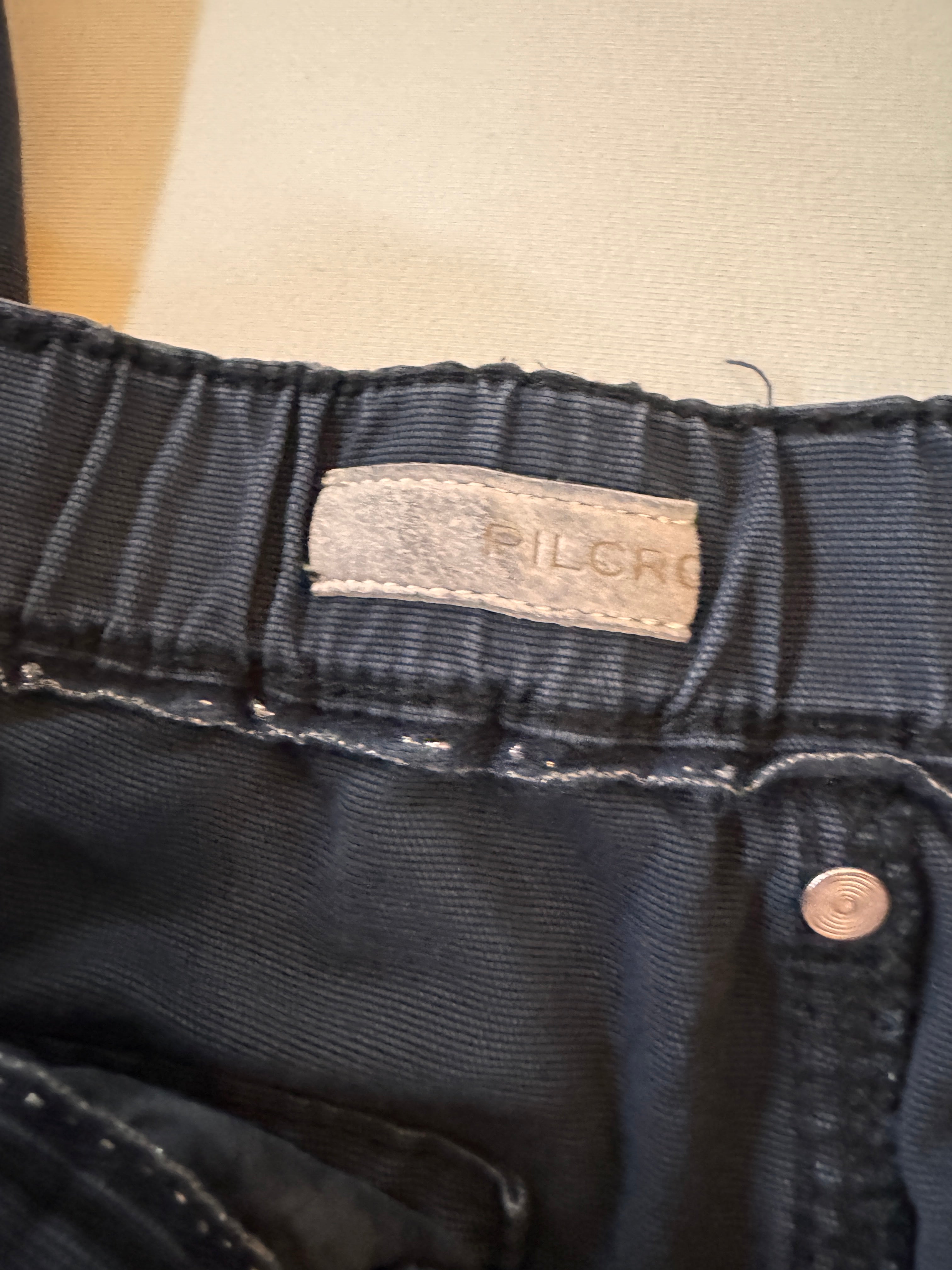 Close-up of dark blue denim fabric with a brand label on a beige background