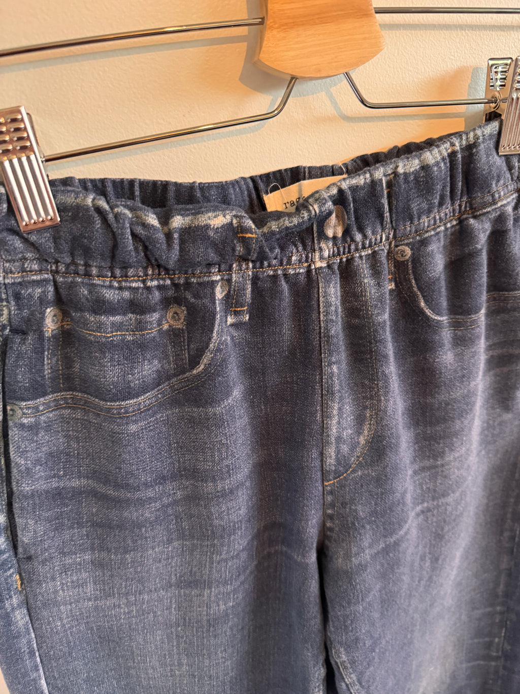 Close-up of a blue denim jeans on a hanger with wooden background