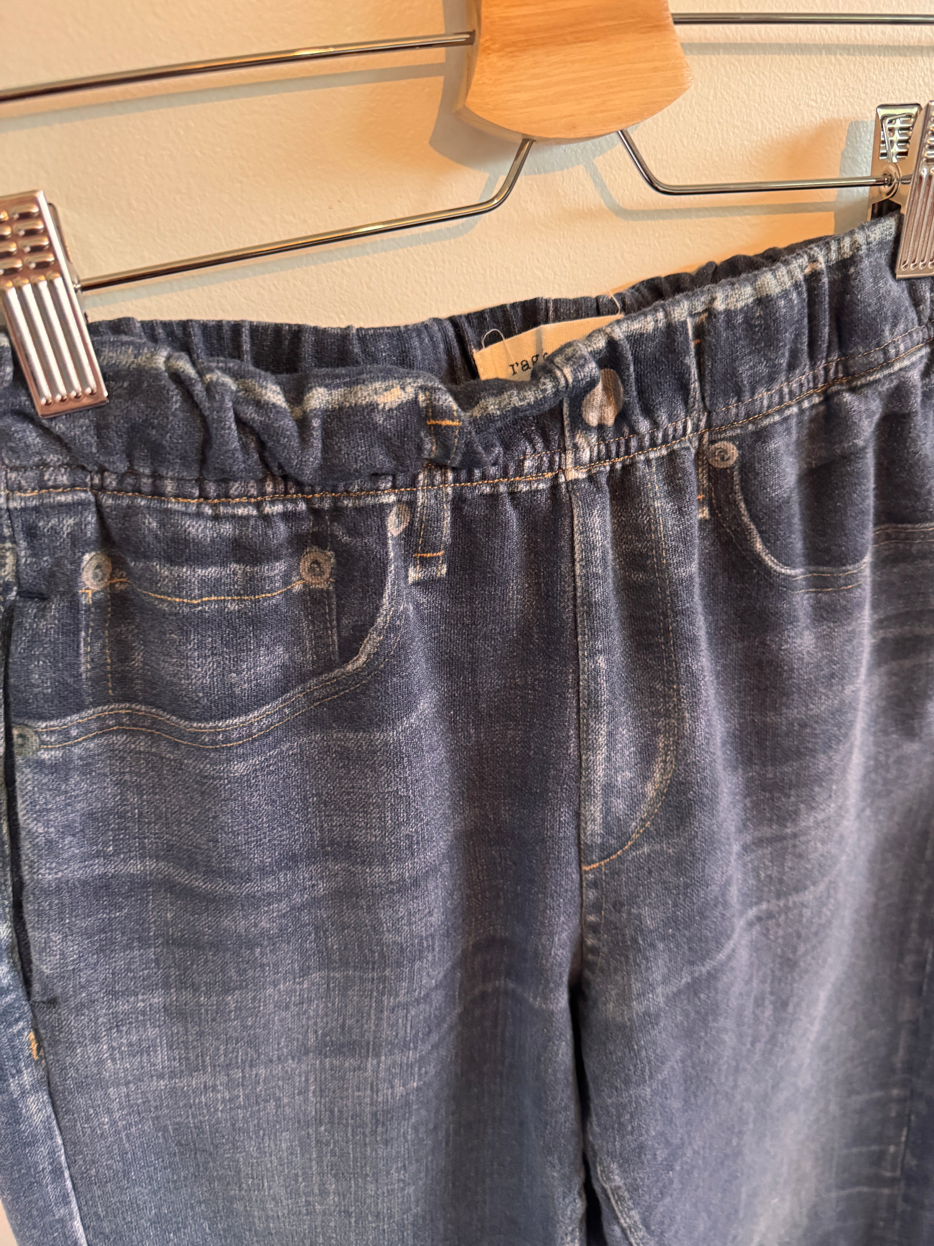 Close-up of a blue denim jeans on a hanger with wooden background