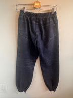 Pair of dark blue jeans on a hanger against a white wall.