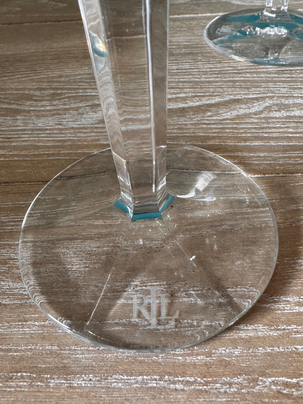 Crystal wine glass with 'RL' branding on a wooden surface