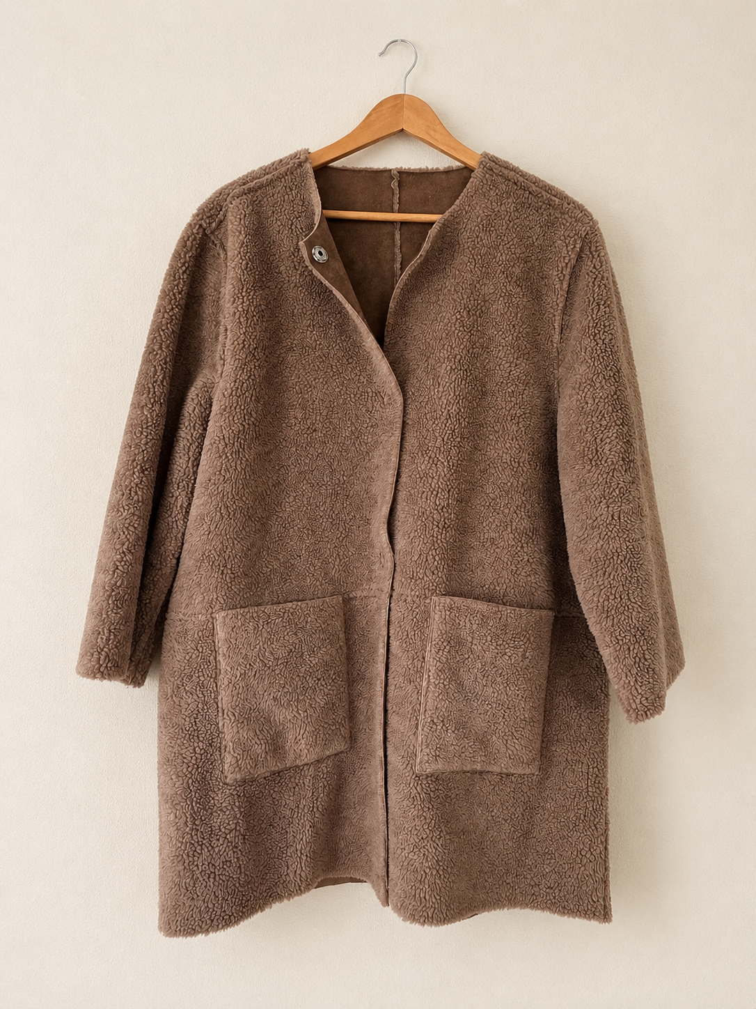 Teddy Coat reversible coat hanging on a light colored background
