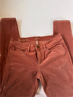 Folded brown pants on a light beige background