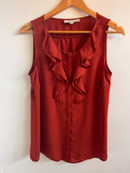 Rust colored top on a wooden hanger against a white background