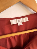 Close-up of a red fabric with a 'LOFT' tag, showing texture and color.