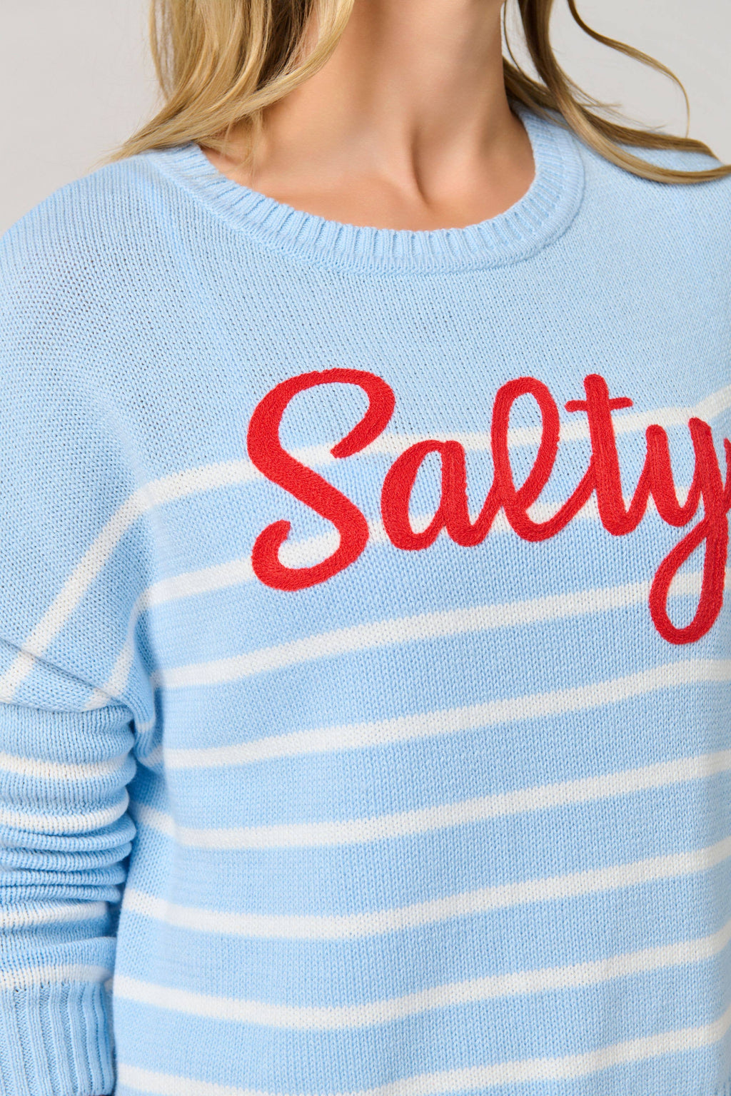 Light blue sweater with white stripes and red 'Salty' text worn by a person.