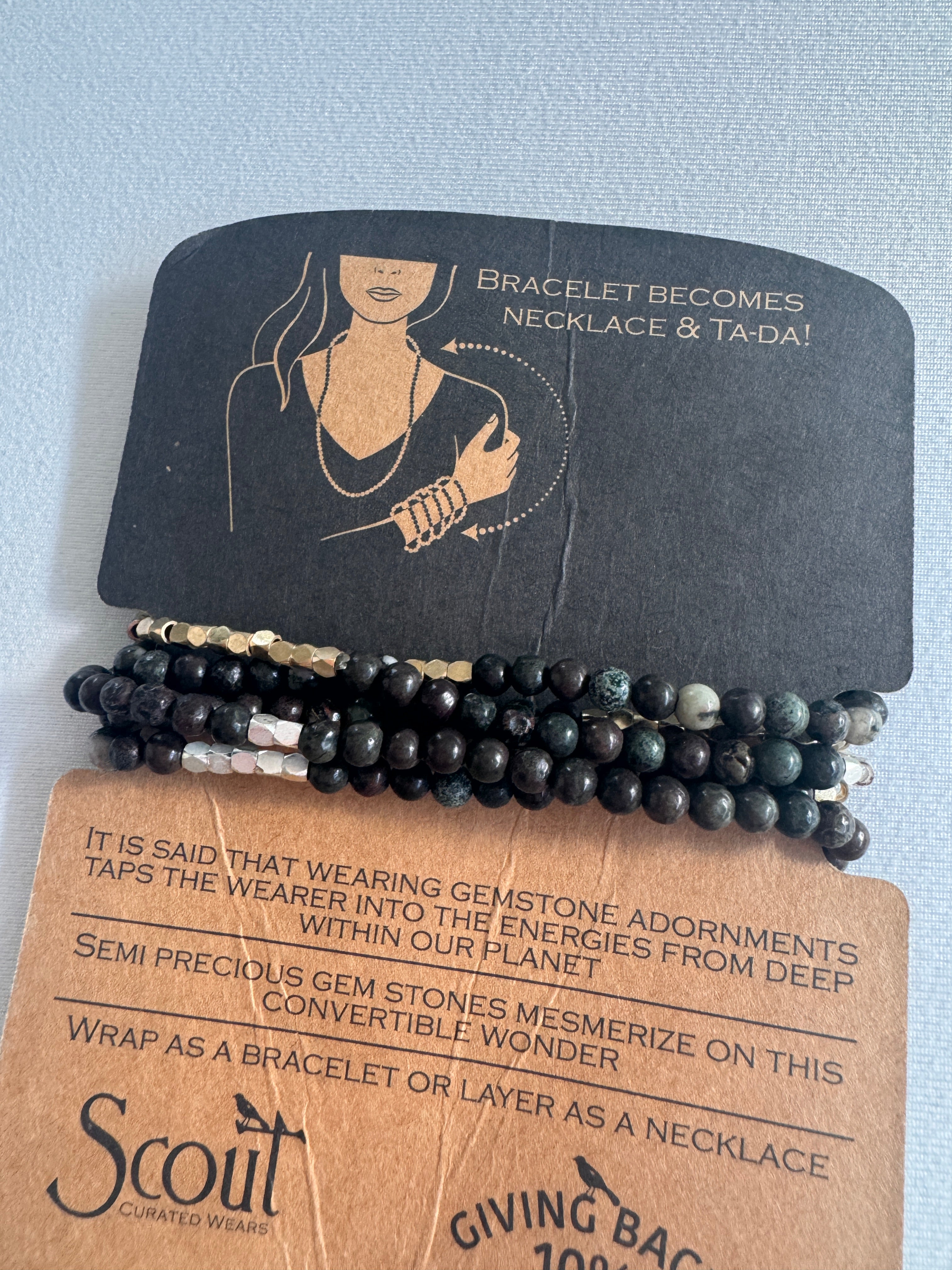 Black beaded bracelet on a cardboard packaging with Scout branding