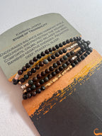 Three black beaded bracelets on a decorative card with text
