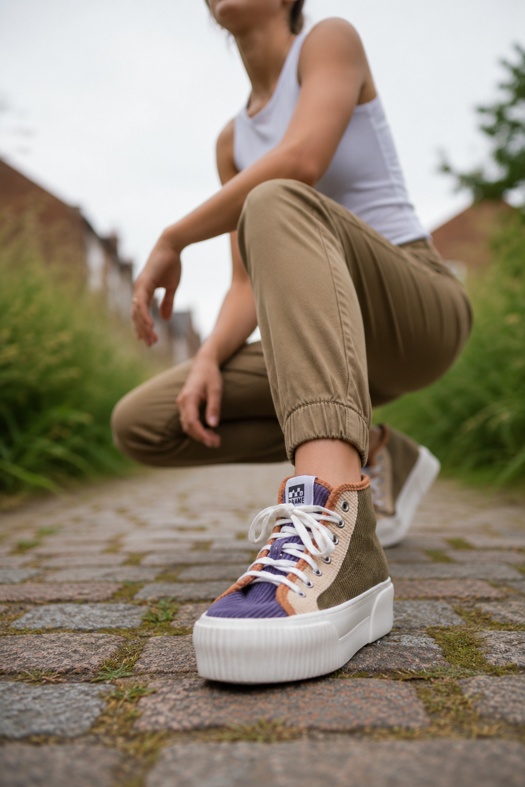 Woman in squat pose with no name shoe on a brick path