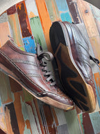 Pair of brown shoes on a multicolored wooden surface