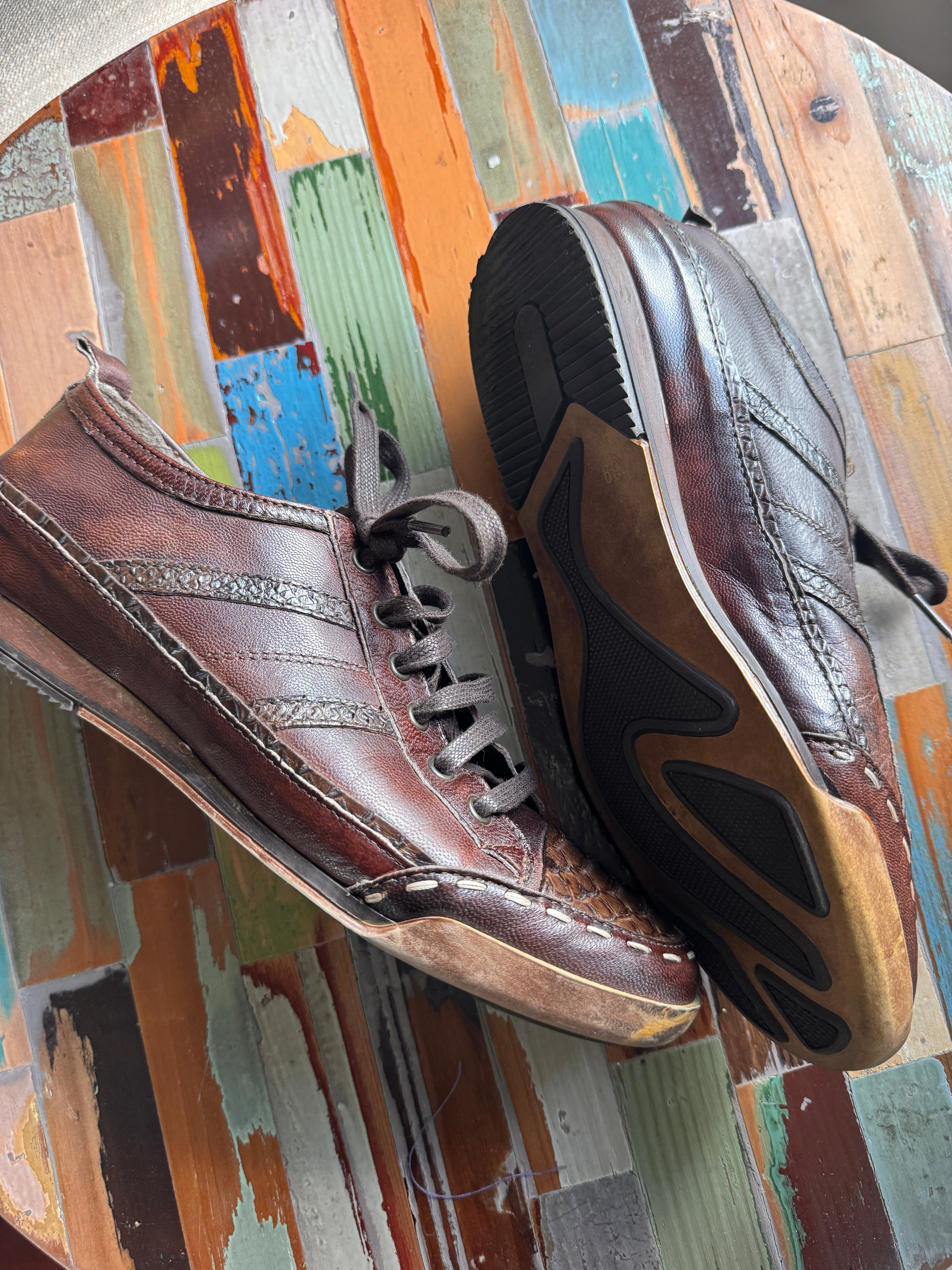 Pair of brown shoes on a multicolored wooden surface