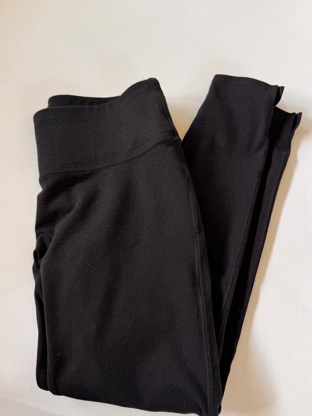 Folded black pants on a light beige background