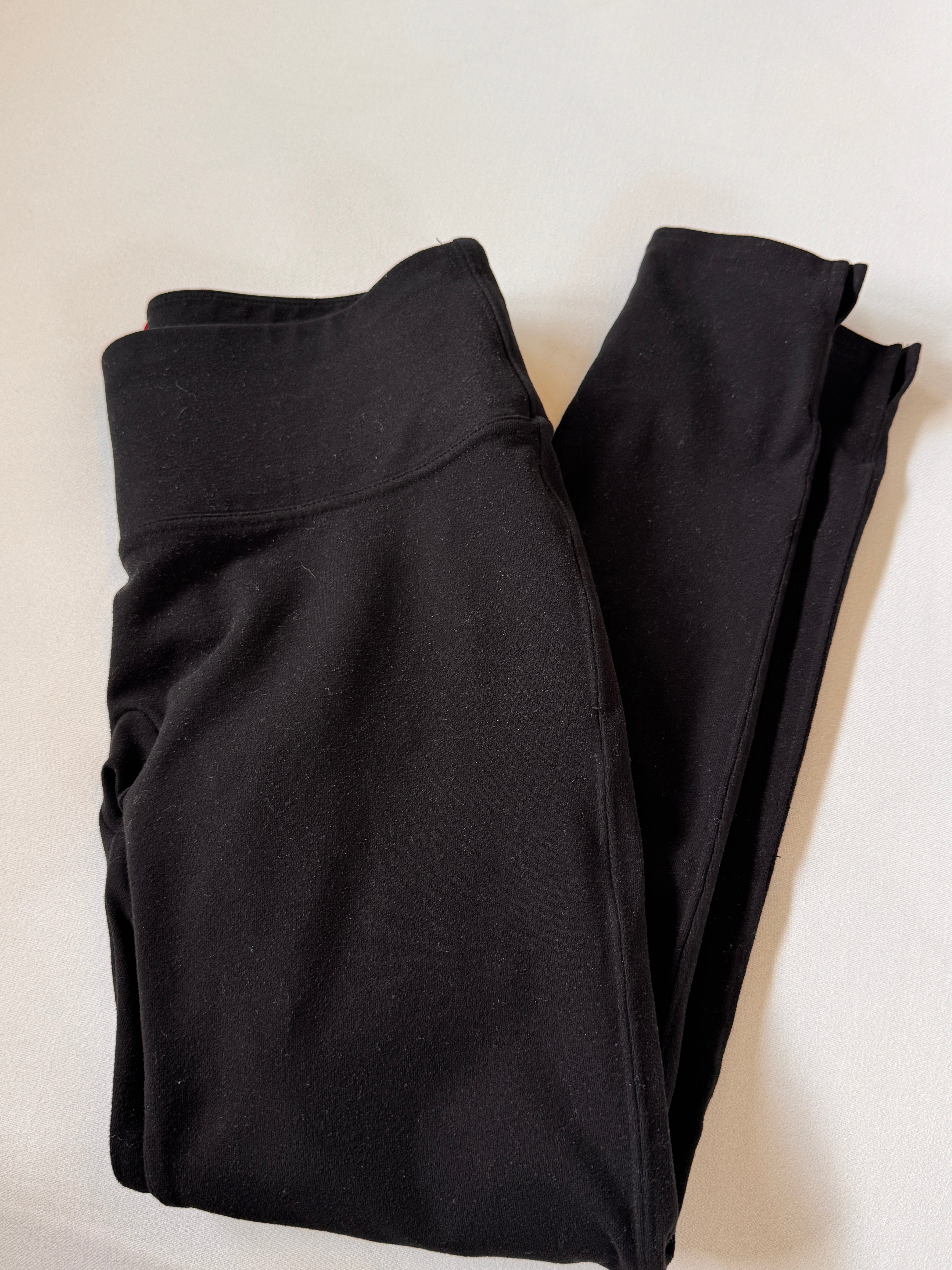 Folded black pants on a light beige background