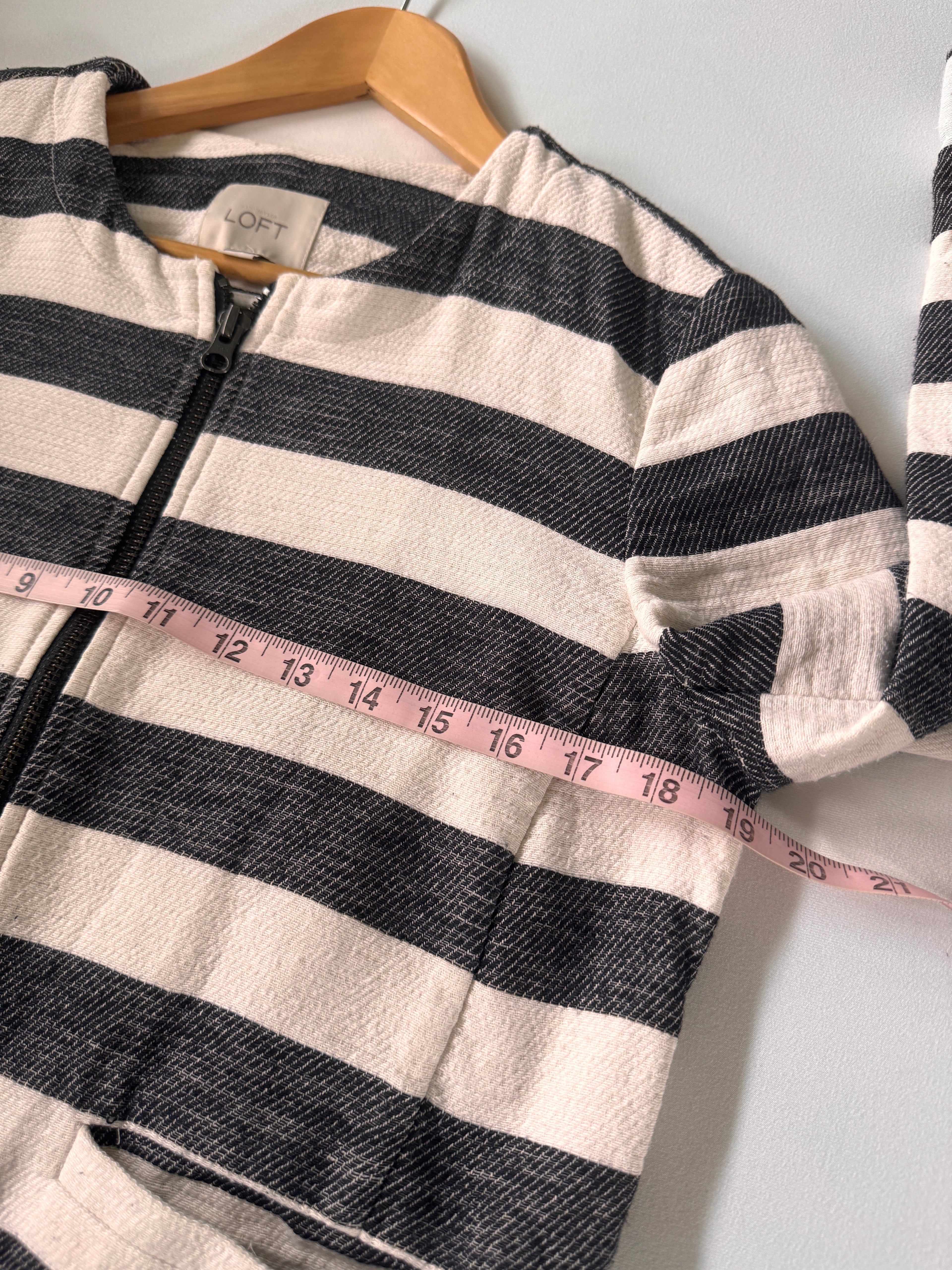 Black and white striped shirt on a hanger with a measuring tape draped over it.