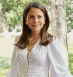 Woman wearing a white dress with gold jewelry in a park setting